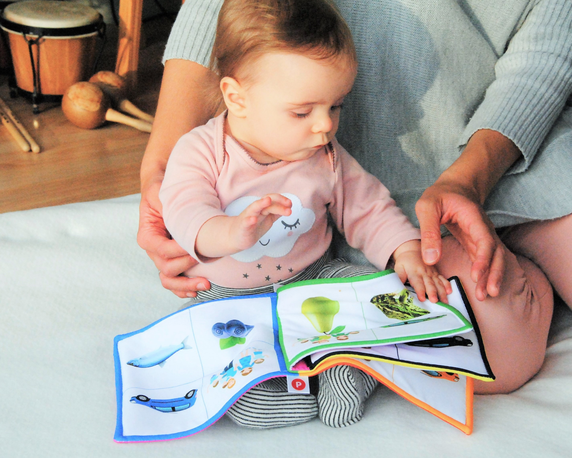 Lapsi on äitinsä sylissä ja lukee kirjaa