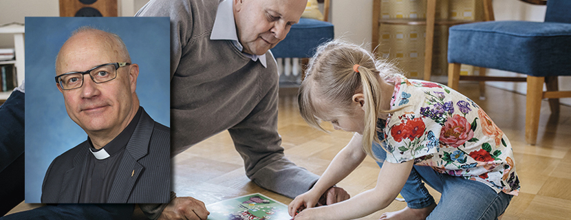 Isoisä leikkii pikkutytön kanssa lattialla. Kuvan päällä näkyy rintakuva Töölön seurakunnan kirkkoherra Han...